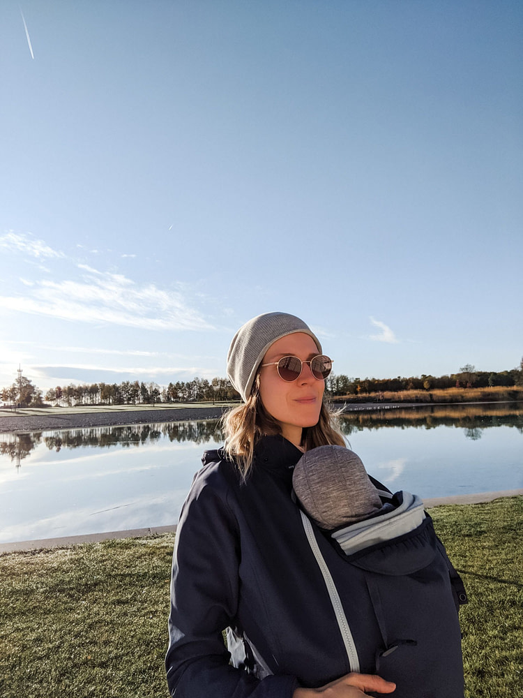 Mom wearing her baby outside under a babywearing jacket Mom wearing her baby outside under a babywearing jacket